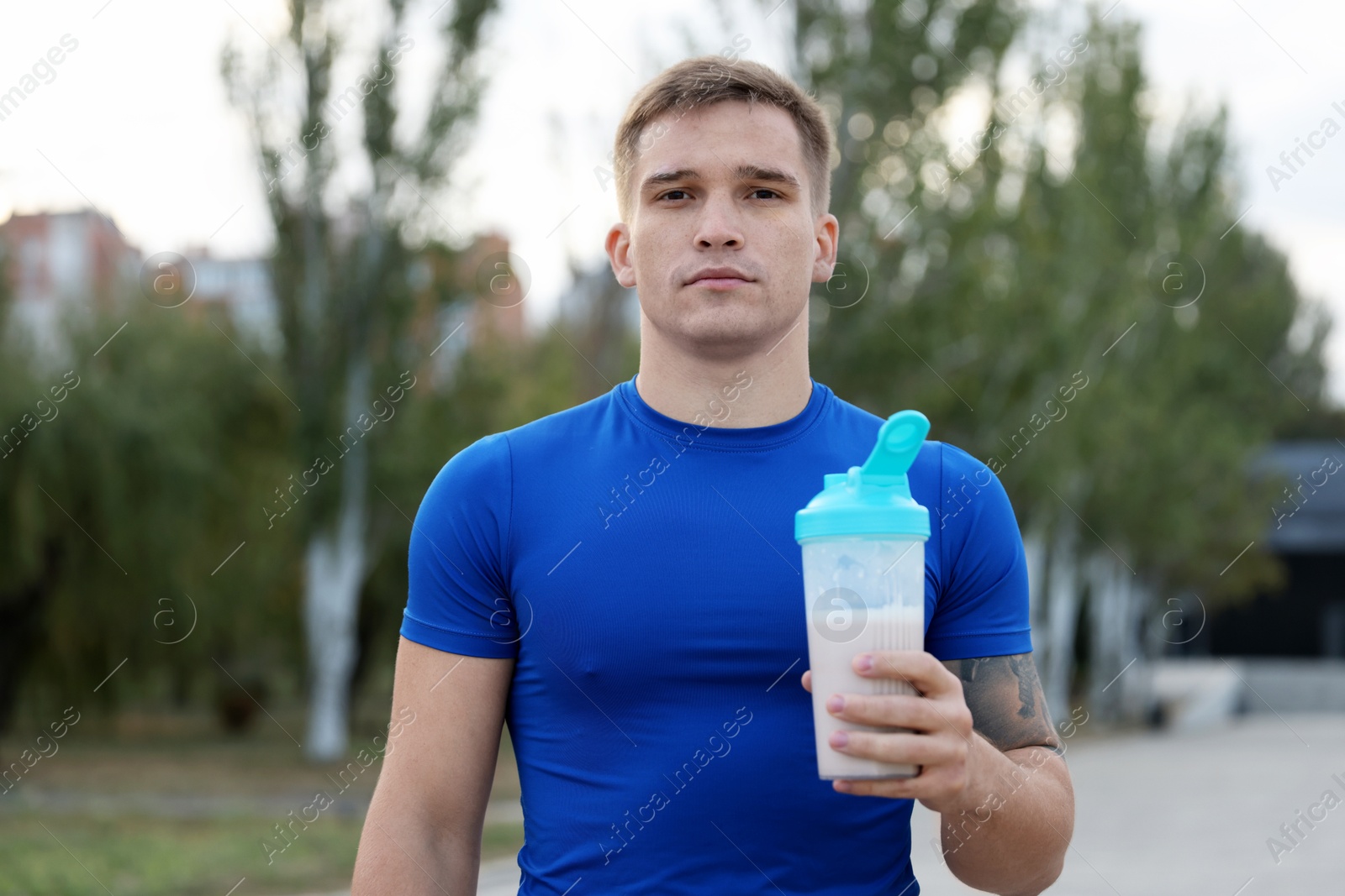 Photo of Athletic man with shaker of protein drink outdoors