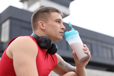 Handsome athletic man drinking protein shake outdoors