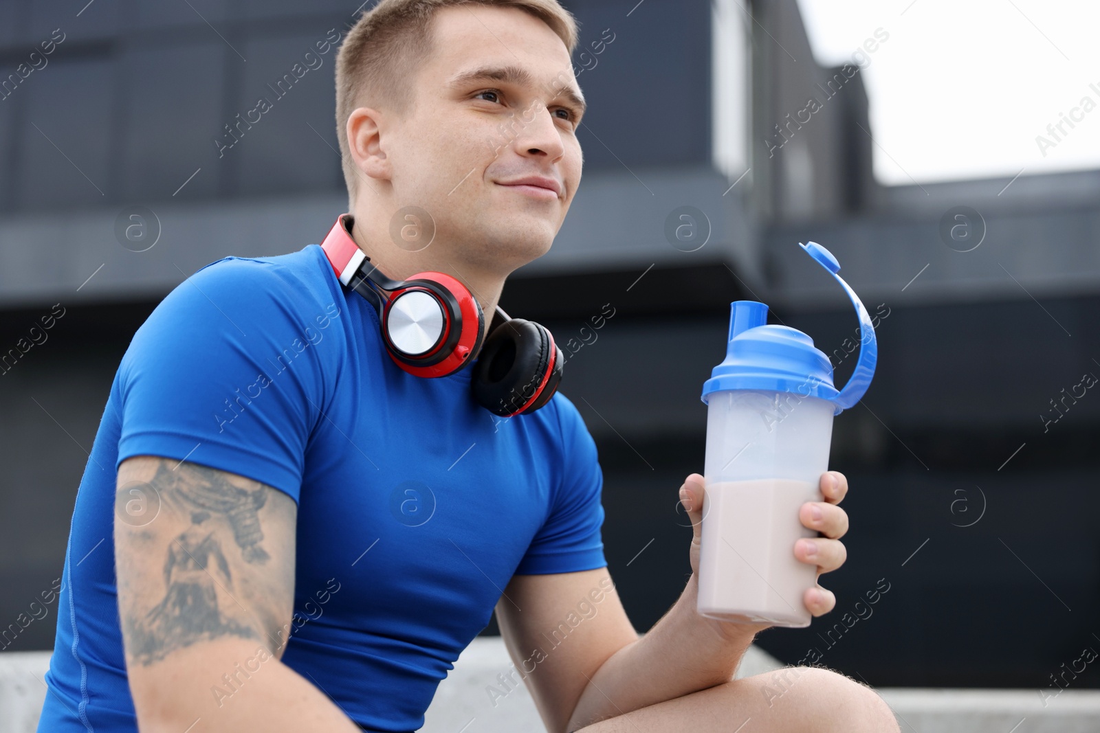 Photo of Athletic man with shaker of protein drink outdoors