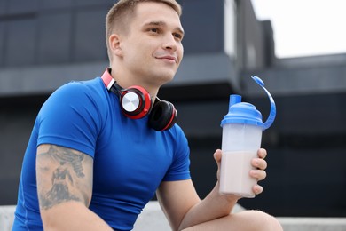 Photo of Athletic man with shaker of protein drink outdoors