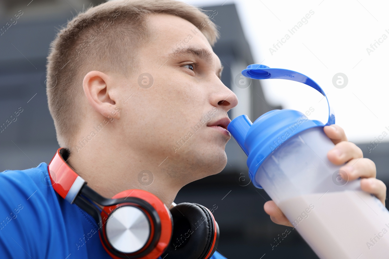 Photo of Handsome athletic man drinking protein shake outdoors