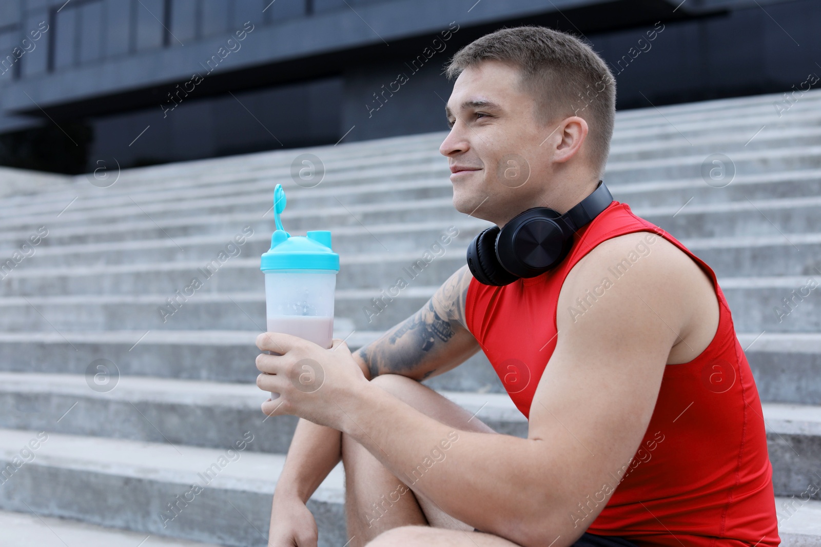 Photo of Athletic man with shaker of protein drink outdoors. Space for text