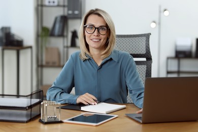 Photo of Businesswoman working on laptop at table in office