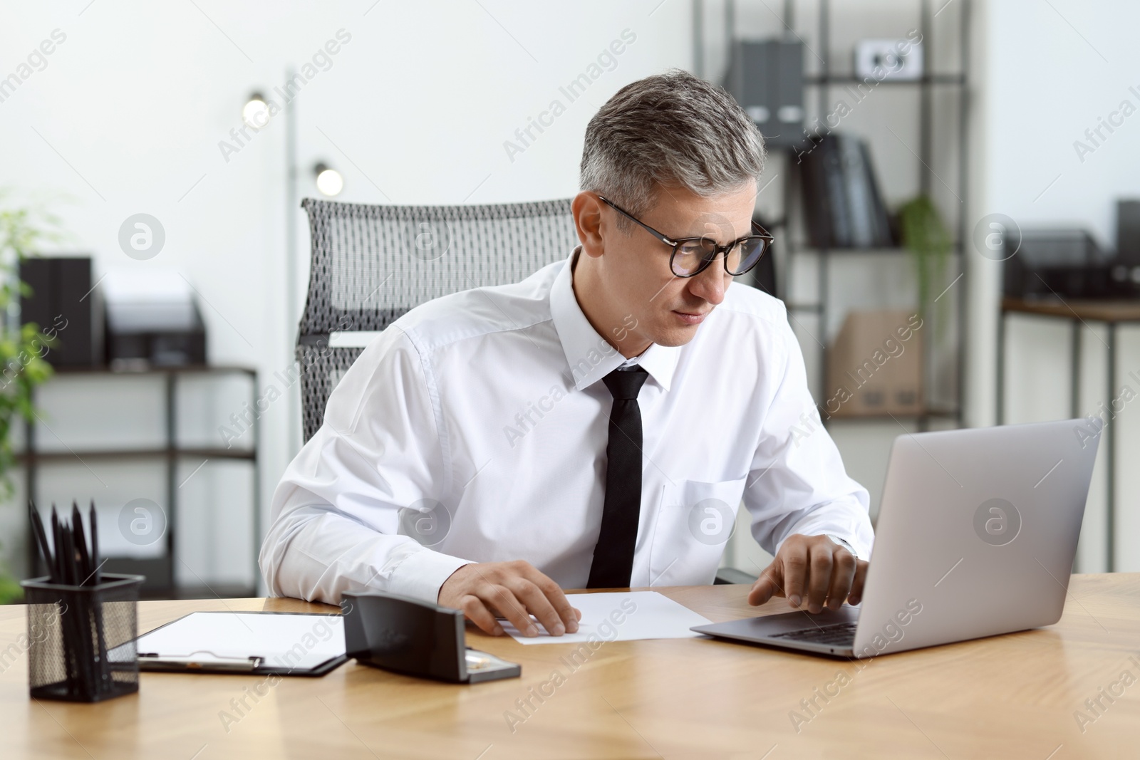 Photo of Businessman working on laptop at table in office