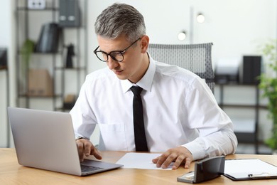 Photo of Businessman working on laptop at table in office