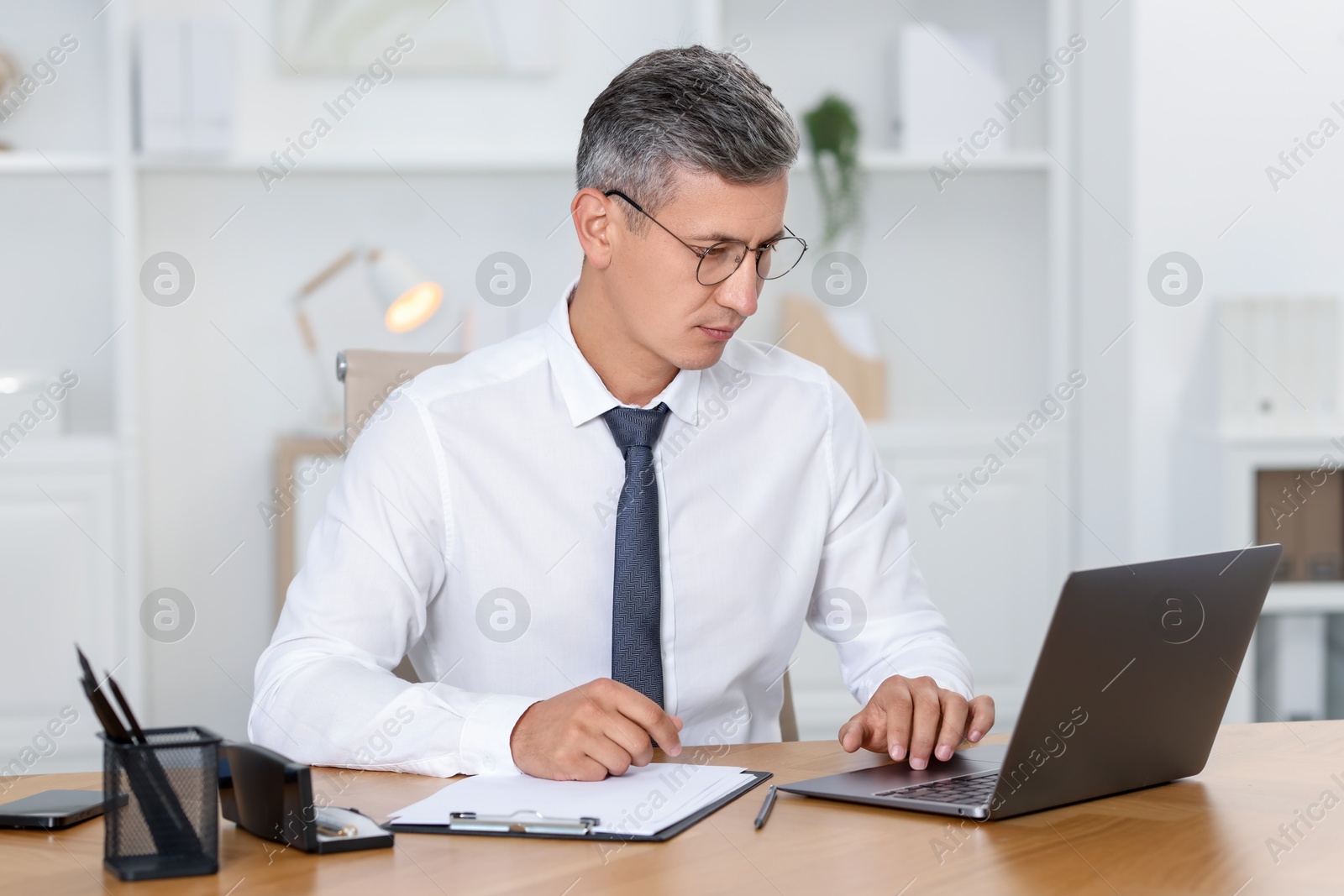 Photo of Businessman working on laptop at table in office