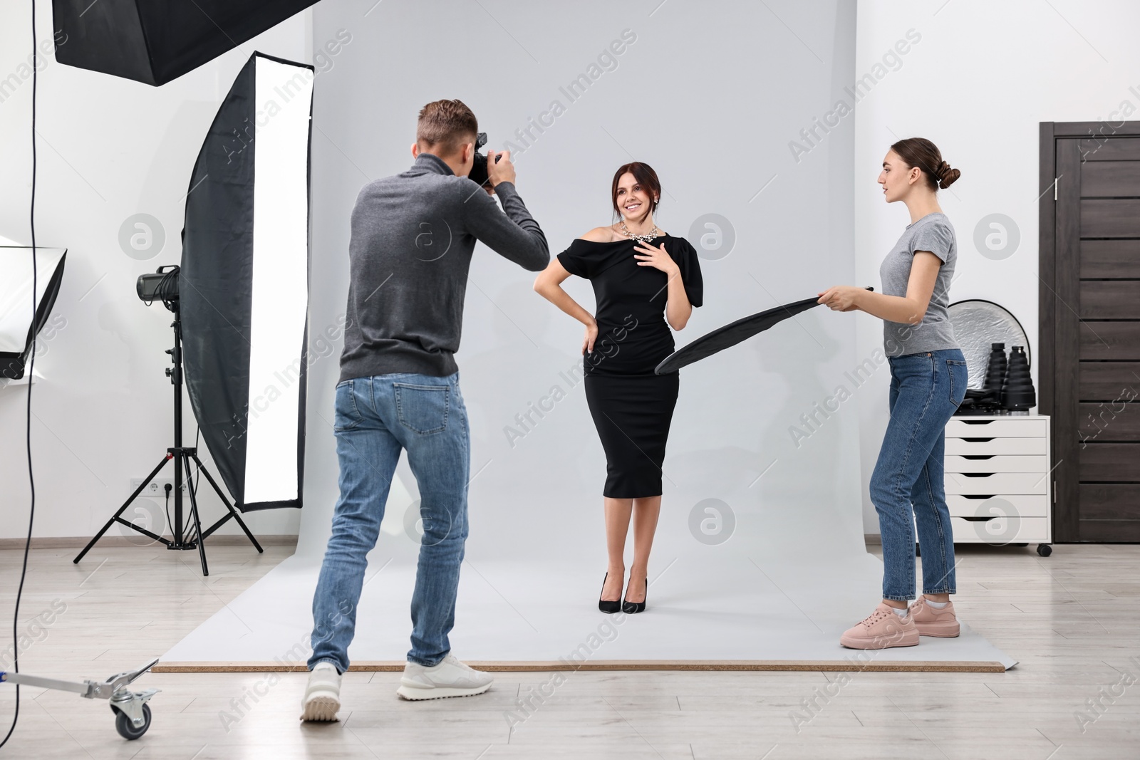 Photo of Photographer and assistant working with model in professional photo studio