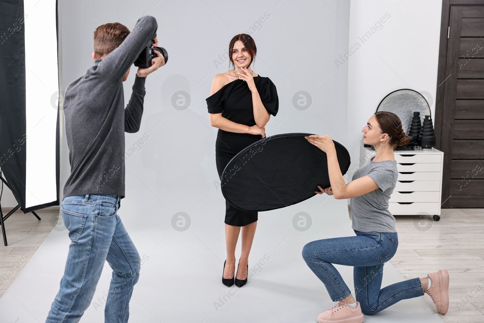 Photo of Photographer and assistant working with model in professional photo studio