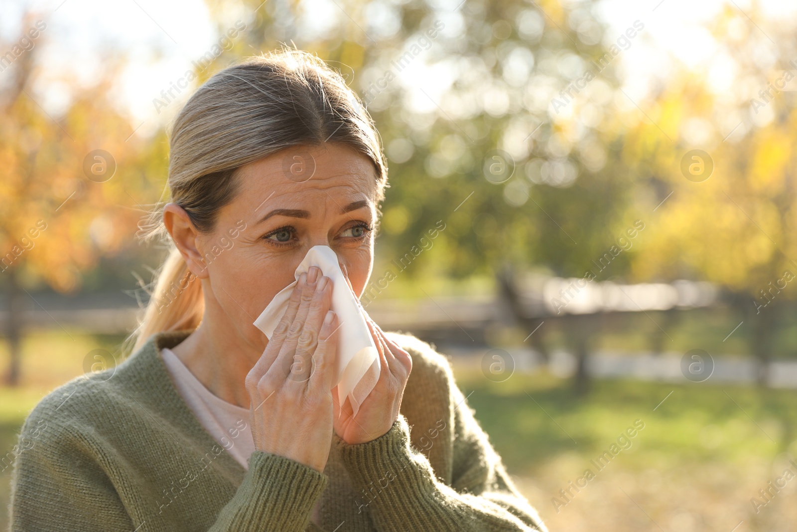 Photo of Woman with runny nose in park, space for text