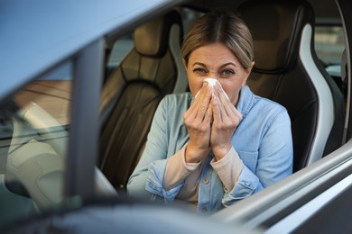 Photo of Woman with tissue blowing runny nose in car