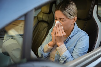 Photo of Woman with tissue blowing runny nose in car