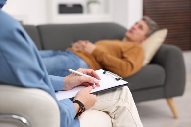 Photo of Professional psychologist working with patient in office, selective focus