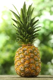 Photo of Fresh ripe pineapple on wooden table against blurred background