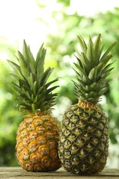 Fresh ripe pineapples on wooden table against blurred background