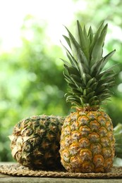 Fresh ripe pineapples on wooden table against blurred background