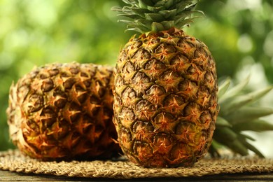 Fresh ripe pineapples on wooden table against blurred background, closeup