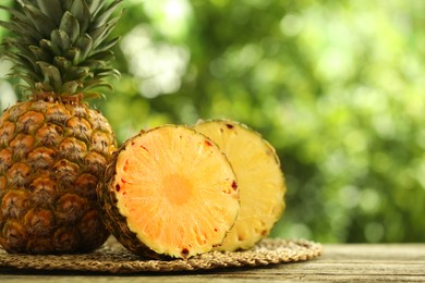 Photo of Fresh ripe pineapples on wooden table against blurred background, closeup. Space for text