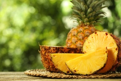 Photo of Fresh ripe pineapples on wooden table against blurred background, closeup. Space for text