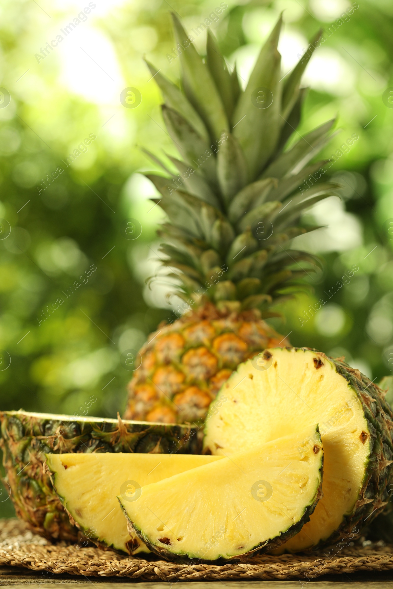 Photo of Fresh ripe pineapples on wooden table against blurred background, closeup