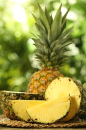 Fresh ripe pineapples on wooden table against blurred background, closeup