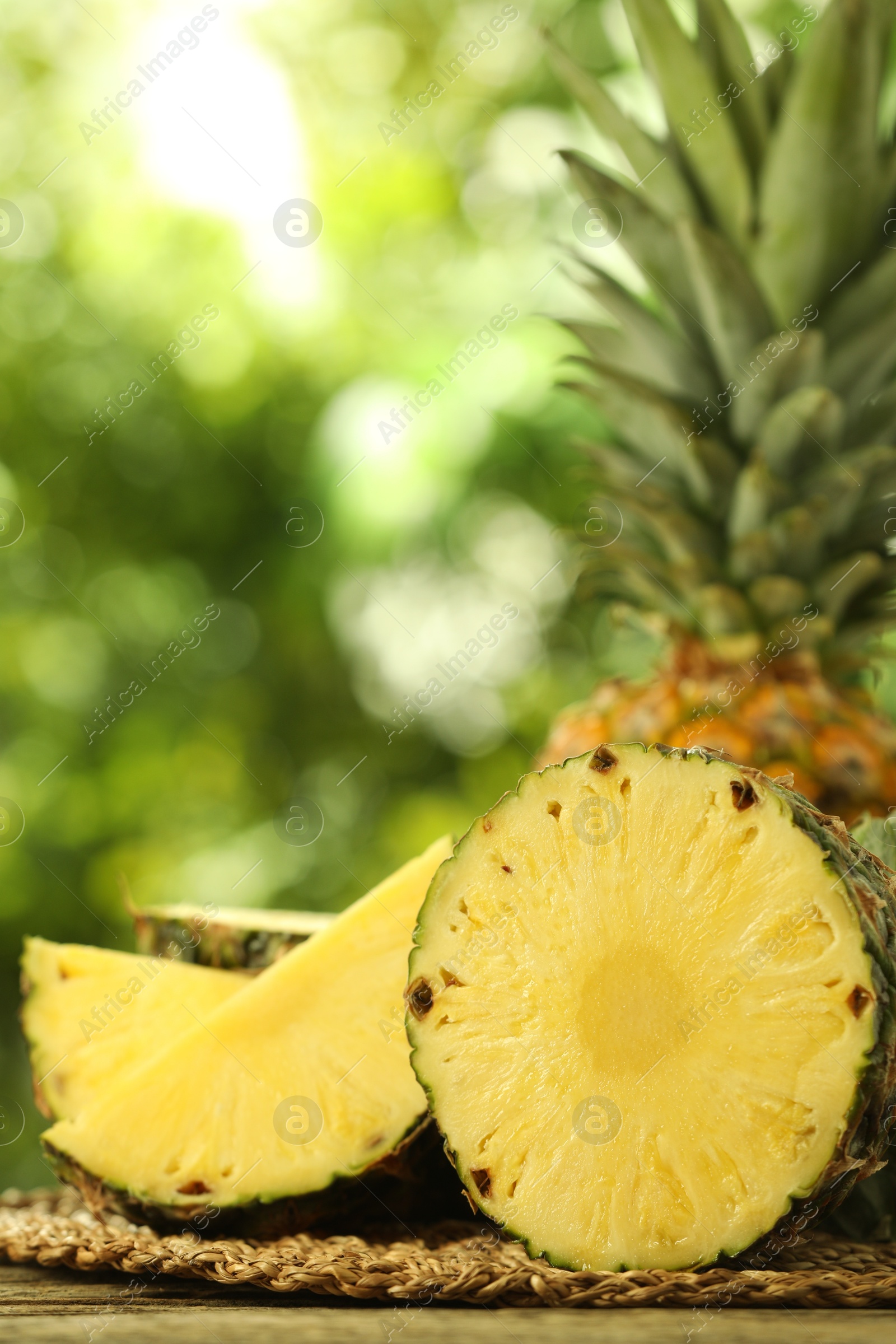 Photo of Fresh ripe pineapples on wooden table against blurred background, closeup