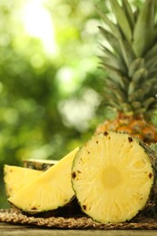 Photo of Fresh ripe pineapples on wooden table against blurred background, closeup