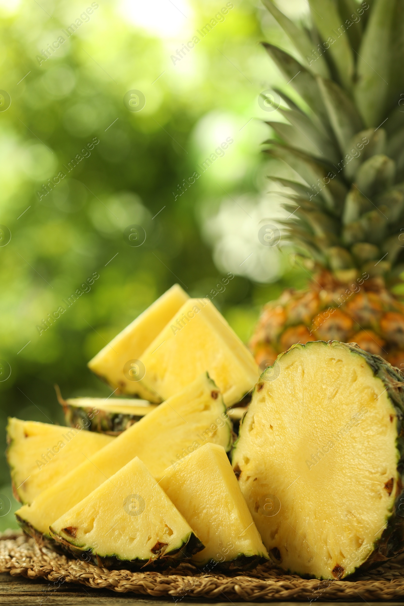 Photo of Fresh ripe pineapples on wooden table against blurred background, closeup