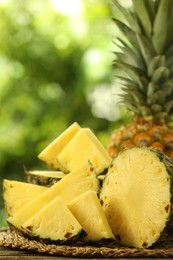 Fresh ripe pineapples on wooden table against blurred background, closeup