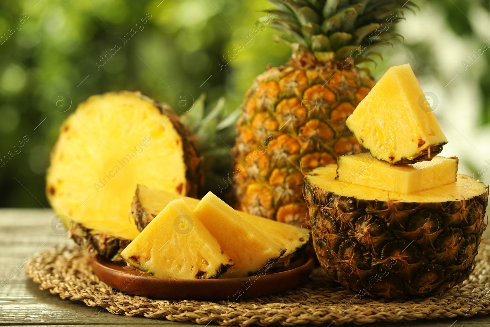 Photo of Fresh ripe pineapples on wooden table against blurred background, closeup