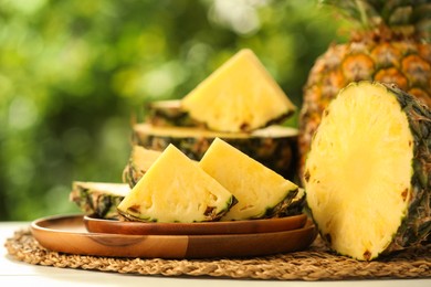 Photo of Fresh ripe pineapples on white wooden table against blurred background, closeup