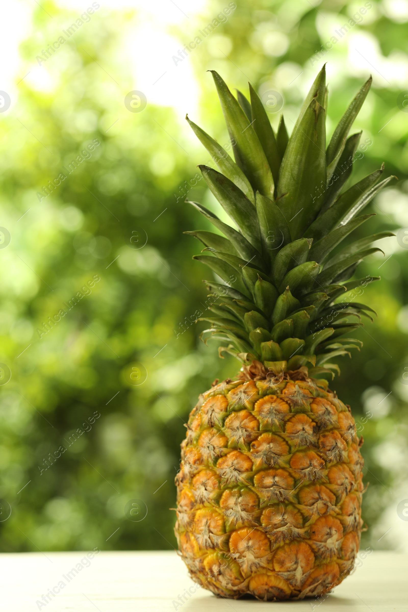 Photo of Fresh ripe pineapple on white wooden table against blurred background