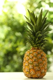 Photo of Fresh ripe pineapple on white wooden table against blurred background