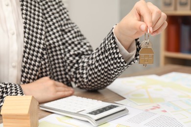 Photo of Real estate agent with house key at table, closeup