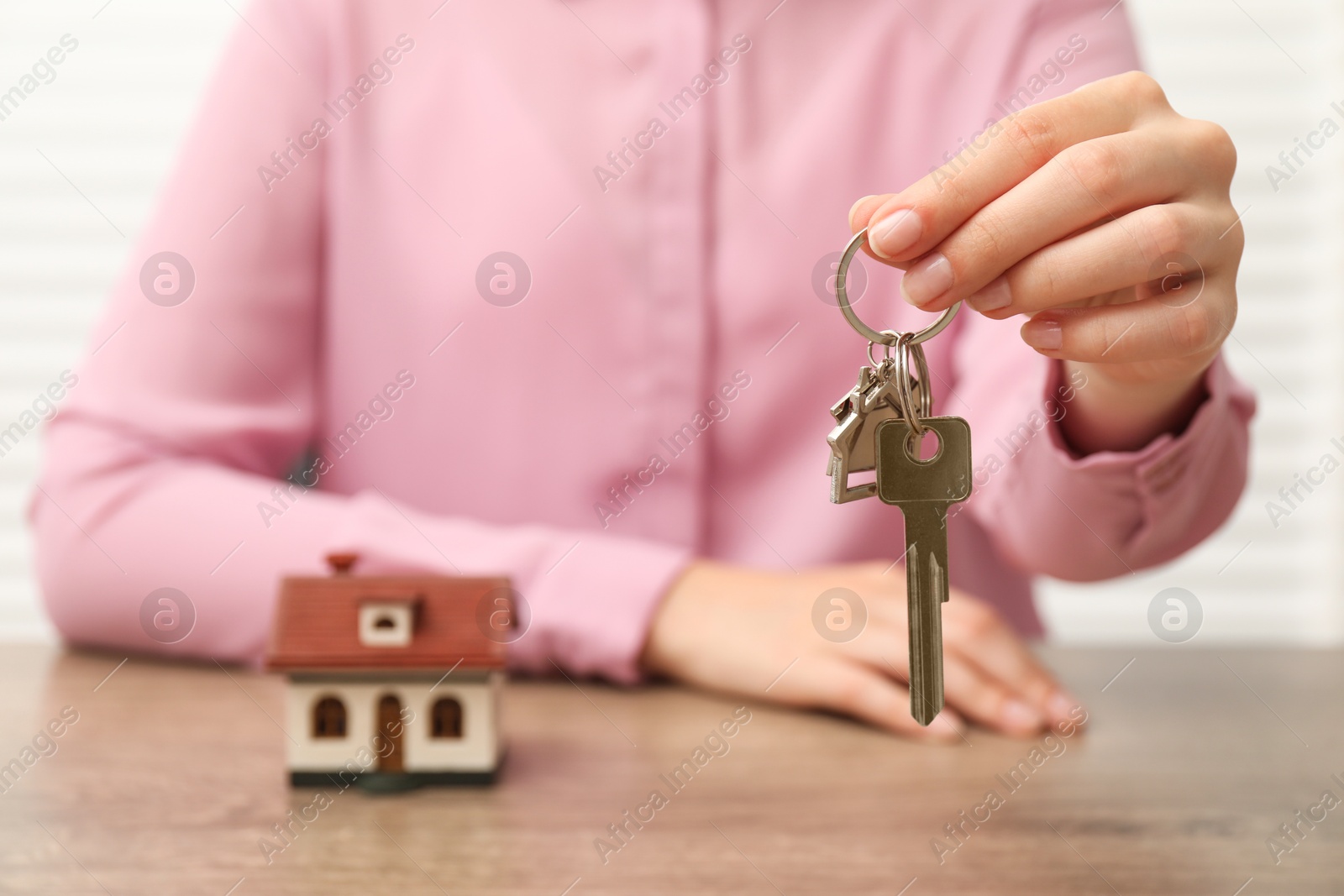 Photo of Real estate agent with house key at table, closeup