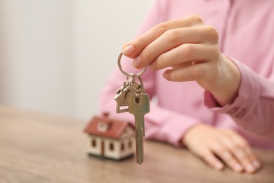 Photo of Real estate agent with house key at table, closeup