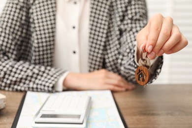 Photo of Real estate agent with house key at table, closeup