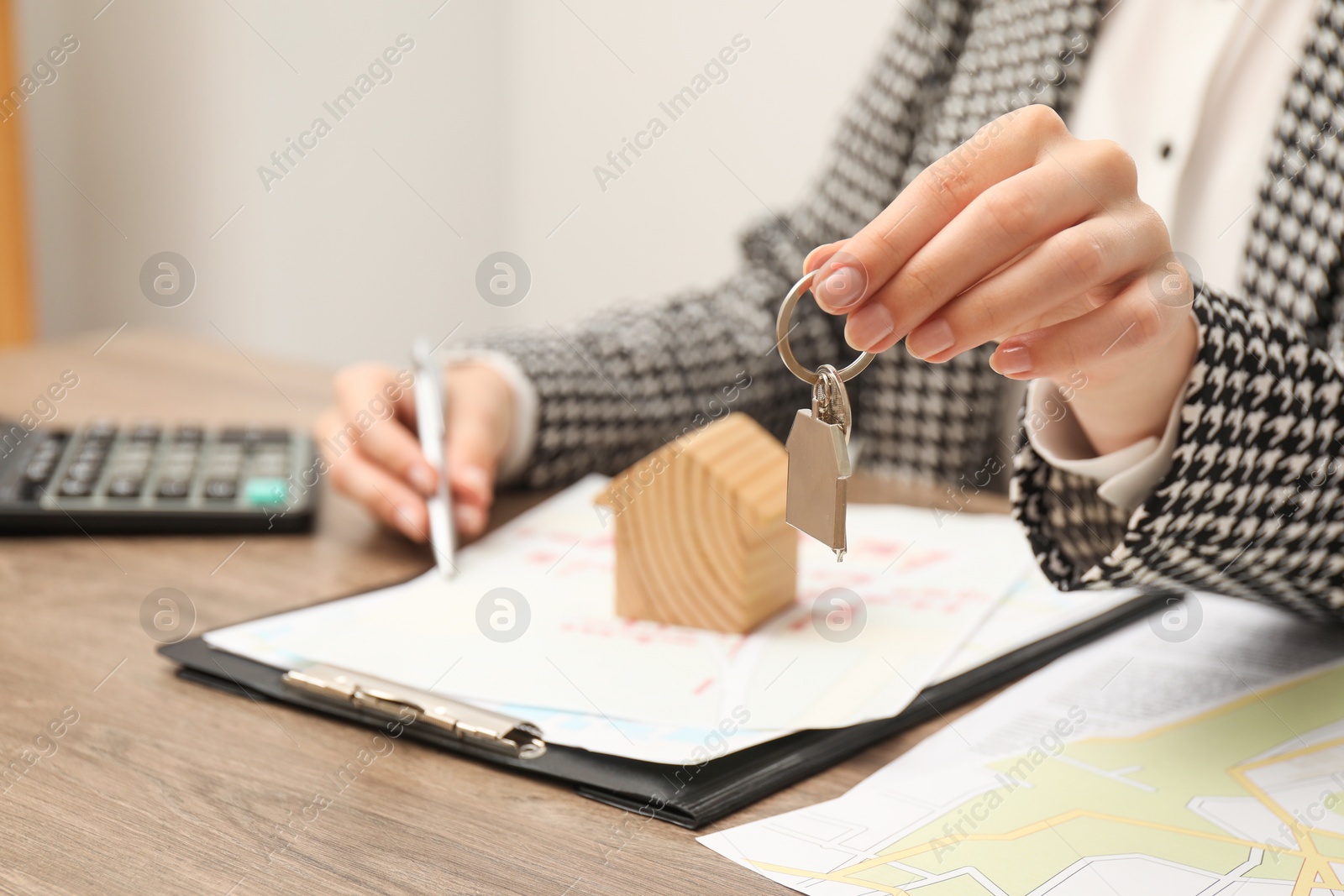 Photo of Real estate agent with house key working at wooden table, closeup