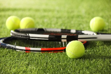 Photo of Tennis rackets and balls on green artificial grass, closeup