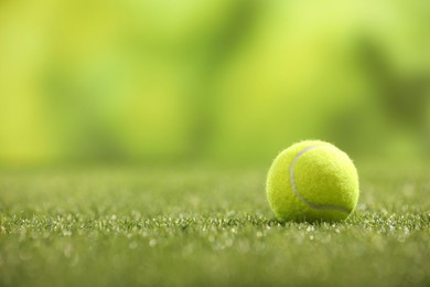 Photo of Tennis ball on green artificial grass, space for text