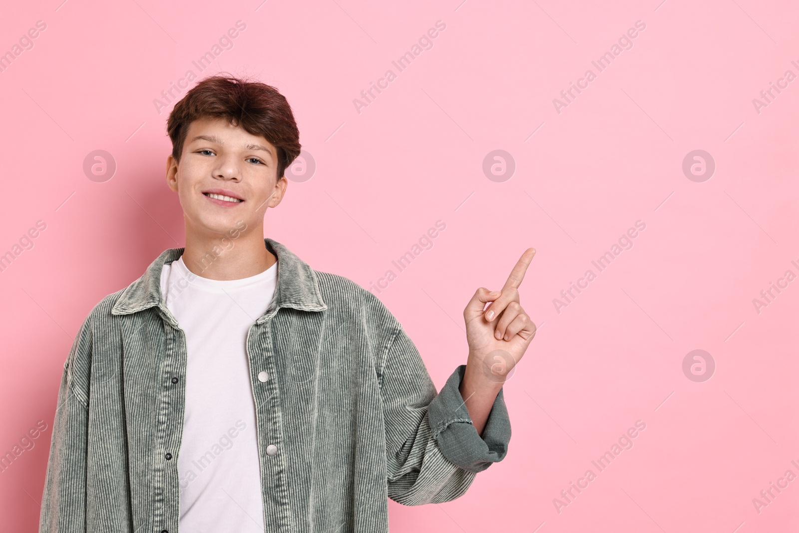 Photo of Happy teenage boy on pink background, space for text