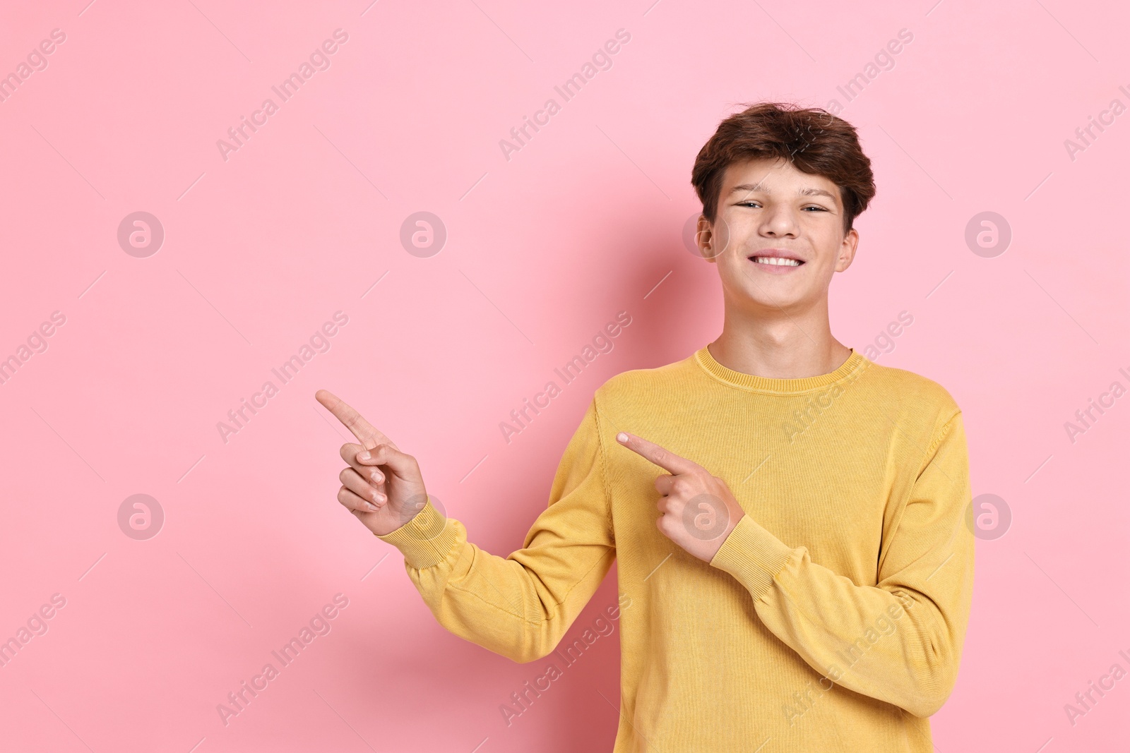 Photo of Portrait of happy teenage boy on pink background, space for text