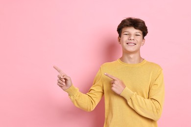 Portrait of happy teenage boy on pink background, space for text