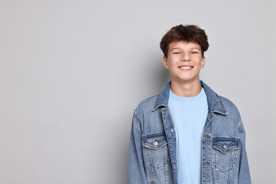 Photo of Portrait of happy teenage boy on light grey background, space for text