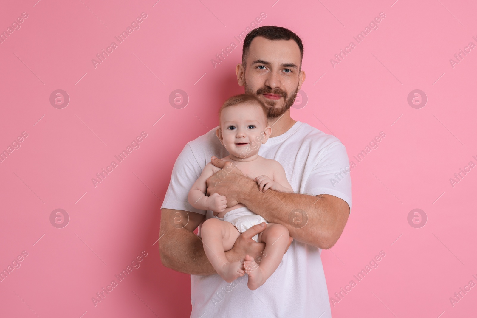 Photo of Father with his cute baby on pink background