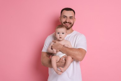 Photo of Father with his cute baby on pink background