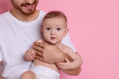 Photo of Father with his cute baby on pink background, space for text