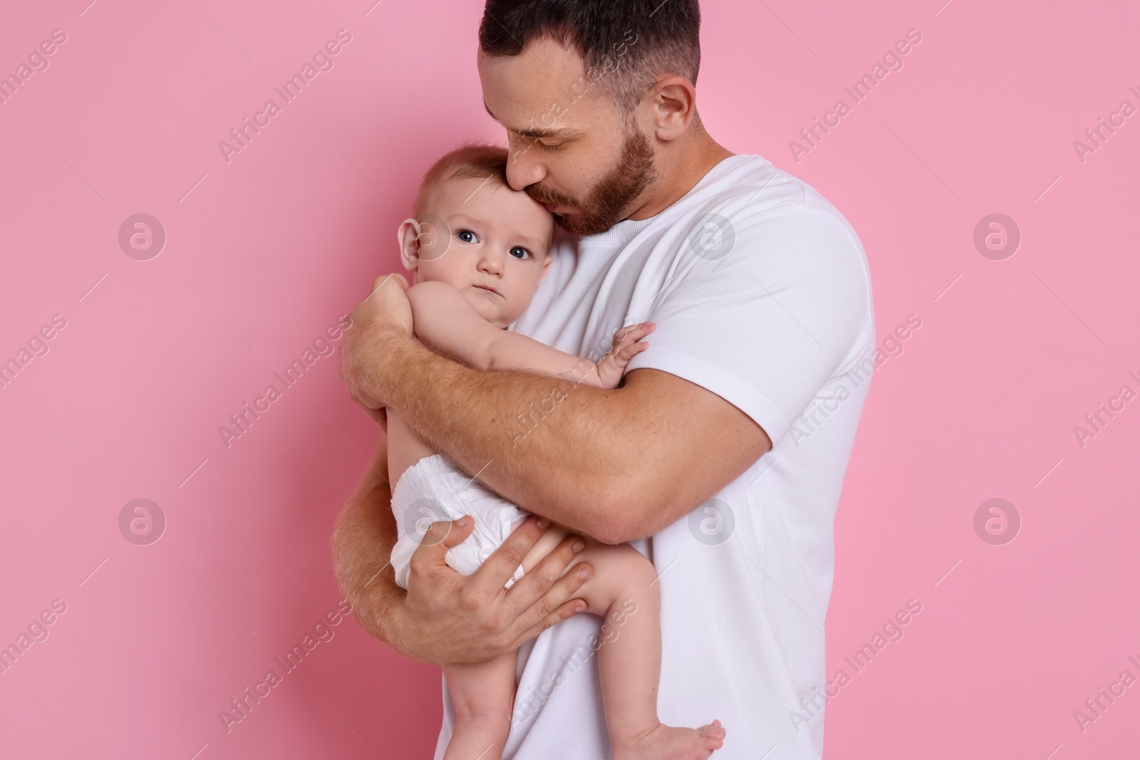 Photo of Father with his cute baby on pink background