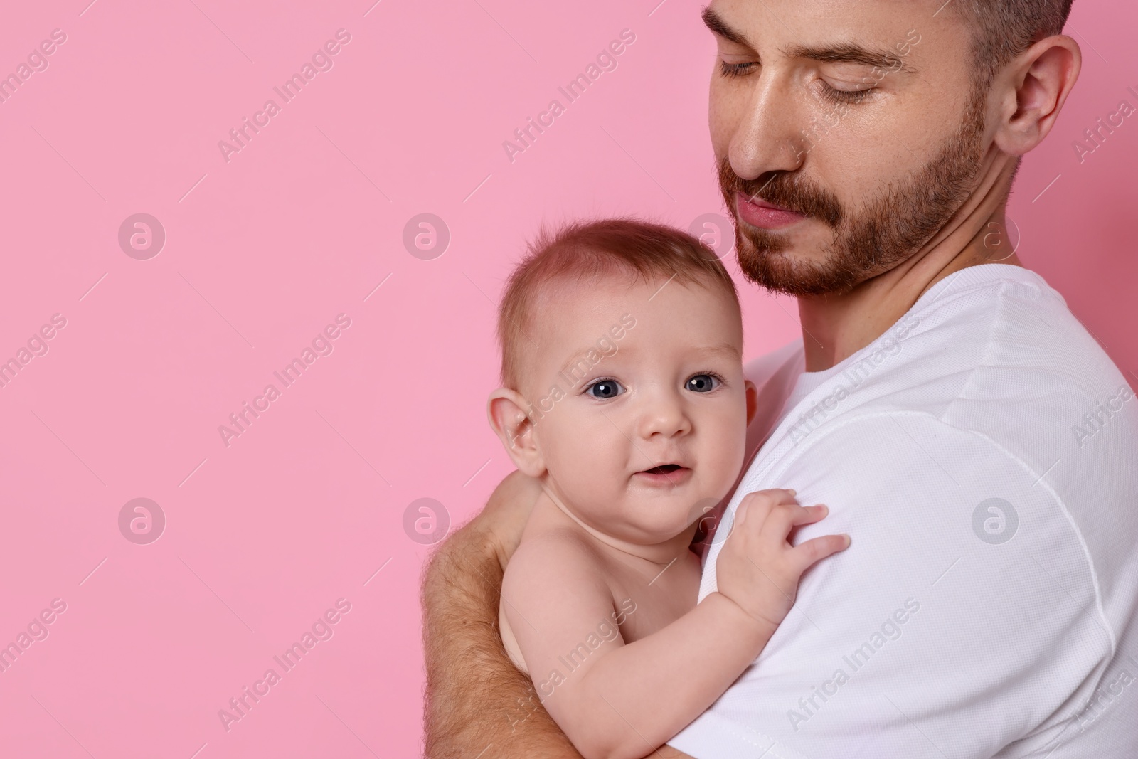 Photo of Father with his cute baby on pink background, closeup. Space for text