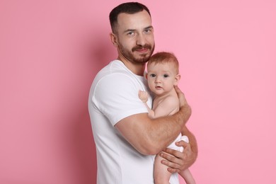 Photo of Father with his cute baby on pink background