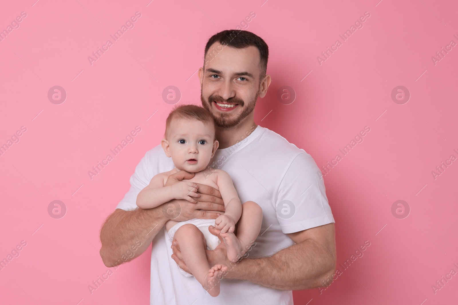 Photo of Father with his cute baby on pink background